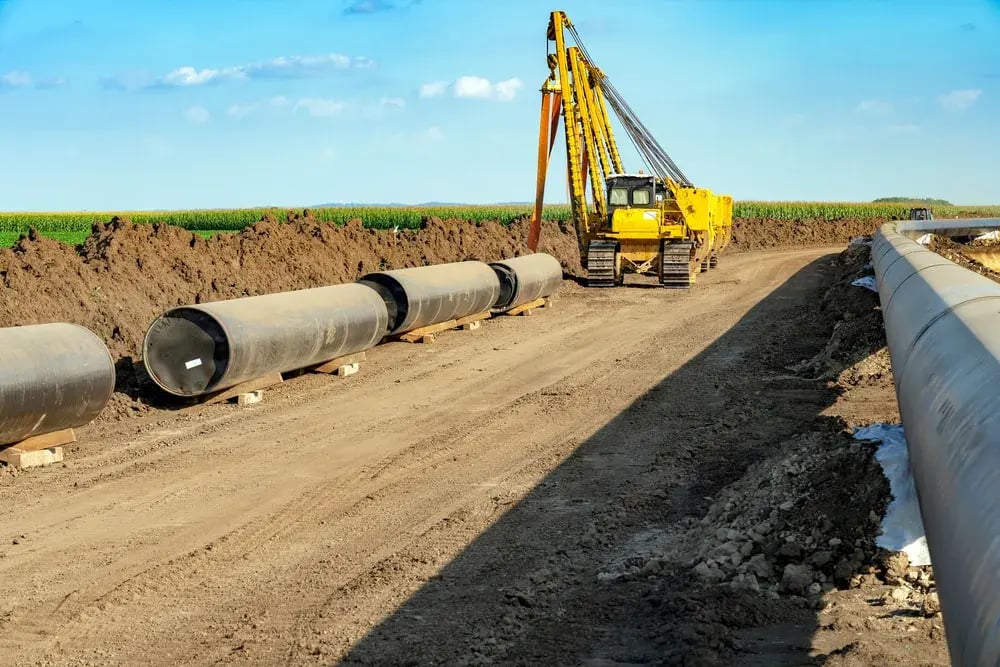 A crane lifts a large pipe, showcasing the equipment's strength and the pipe's industrial context.