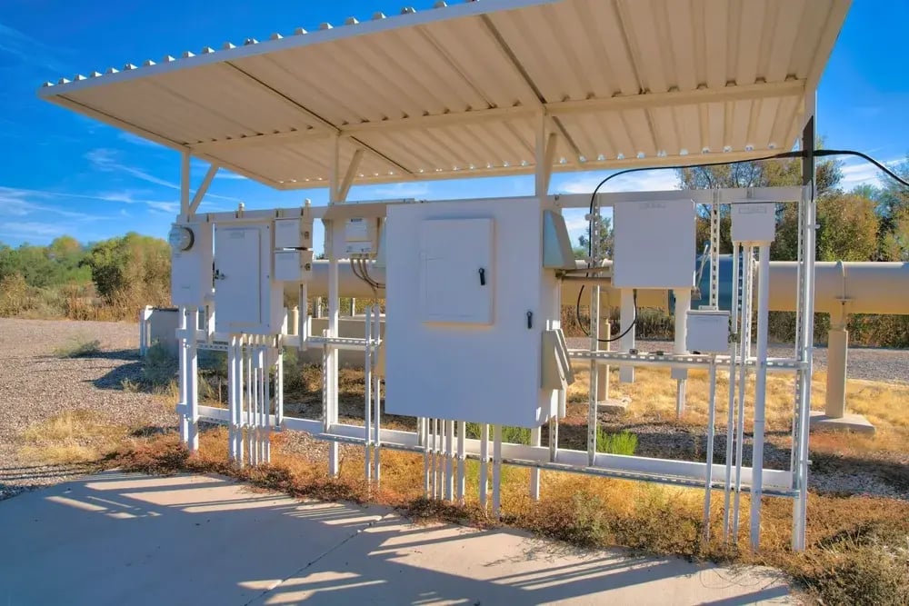 A white building featuring a metal roof and visible pipes, set against a clear blue sky.