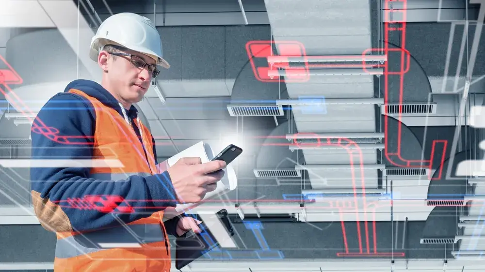 Construction professional wearing a hard hat and safety vest uses a smartphone while reviewing building plans, with digital HVAC and piping schematics overlaid across the mechanical room.